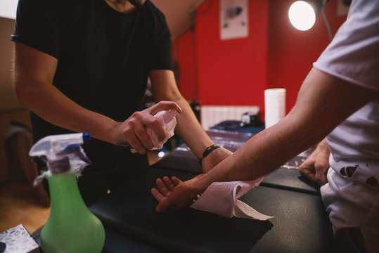 Tattoo artists sterilising carefully customers arm before tattooing it.