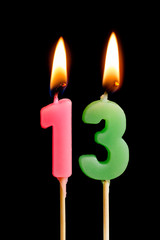 Burning candles in the form of 13 thirteen figures (numbers, dates) for cake isolated on black background. The concept of celebrating a birthday, anniversary, important date, holiday, table setting