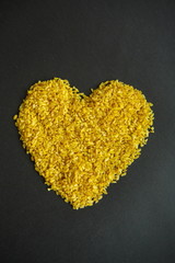 Croup of bulgur placer, pile on a black background lined in the form of a symbol of the heart, love, valentine. The product is rich in protein, healthy food, vegetarianism. View from above
