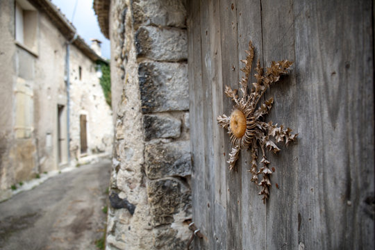 Ruelle village d'ard&egrave;che avec cardabelle des causses s&eacute;ch&eacute;e  famille de l&rsquo;artichaud cardouille cardon sur porte en bois rituel protection animaux 