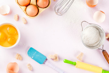 Ingredients and utensils for cooking baking egg, flour, sugar, whisk, rolling pin, on light pink background, copy space top view frame