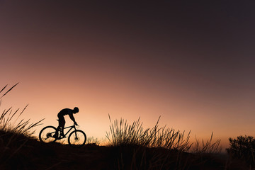 Silhouette of man riding bicycle during sunset