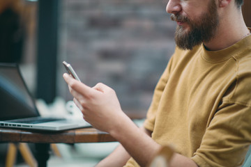 Young man sitting in cafe and using smart phone.