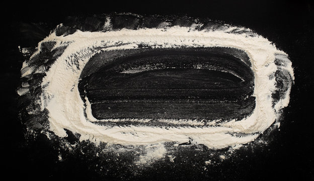 background with flour sprinkled on a black table with a rolling pin on the side