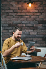 Young man sitting in cafe and using tablet.