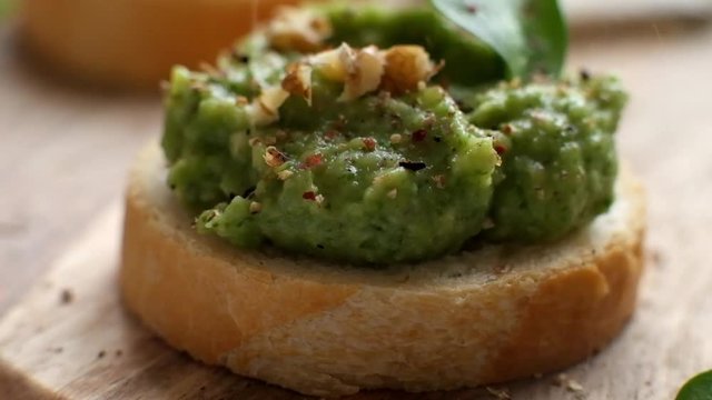 Slow motion food: large grains of pepper fall on toast with avocado spead