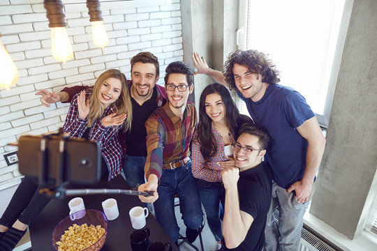 A group of friends are photographed on a phone indoors.