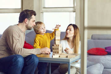 A child with parents plays table games on the table in the house.