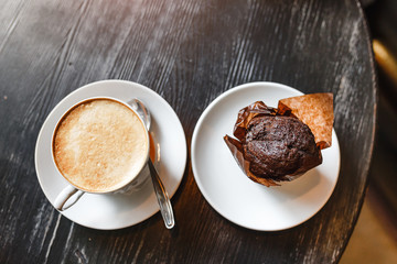 Coffee with chocolate muffin on old wooden table in cafe. Top view