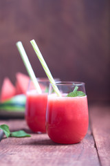 Fresh watermelon cocktail in two glasses on a dark wooden rustic background