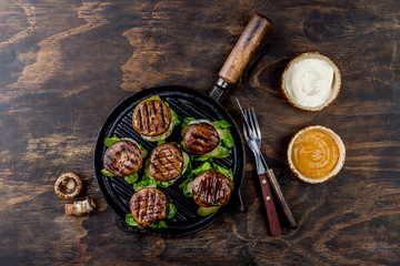 Grilled portobello bun mushroom burgers on cast iron grill pan ob wooden background, top view