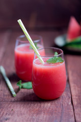 Fresh watermelon smoothie in two glasses on a dark wooden rustic background
