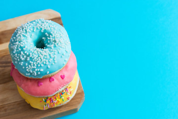 Three colorful frosting fried american donuts blue background