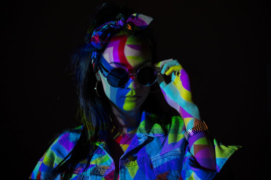 Woman in sunglasses with geometric colorful light on face