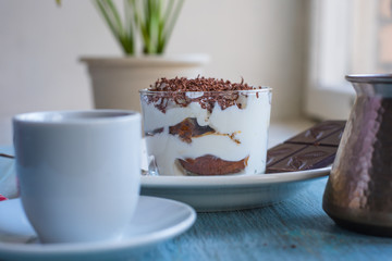 Homemade Italian dessert tiramisu and coffee on the table by the window
