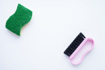 Cleaning Concept. Set of yellow, green, blue, red, white and pink cleaning tools: rags, sponges, brushes, dishwashing liquid, rubber gloves on the white background, top view, flat lay, close up