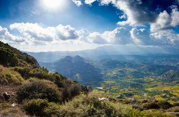 Patchwork landscape and mountain against cloudy sky