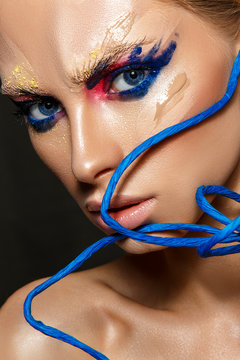 Beautiful woman portrait with blue art on face and rope.