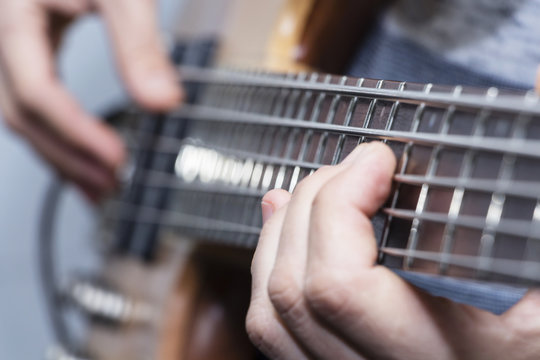Closeup photo of bass guitar player hands, soft selective focus, live music theme