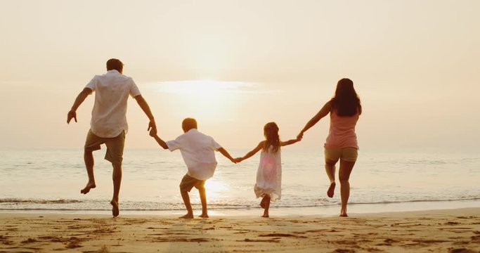 Happy young family playing on the beach at sunset