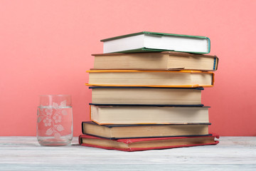 Book stacking. Open book, hardback books on wooden table and pink background. Back to school. Copy space for text.