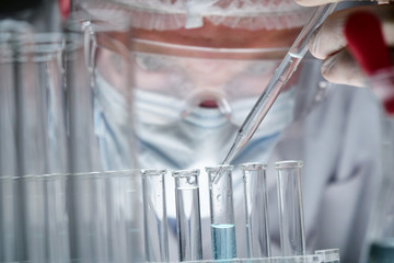 In a futuristic laboratory, a scientist with a pipette analyzes a colored liquid to extract the DNA and molecules in the test tubes.Concept:research,bmented reality, biochemistry, immersive technology
