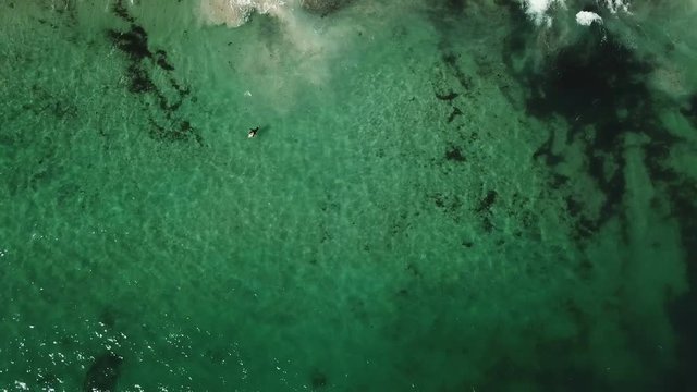 Waves breaking on beach with surfers aerial view from drone