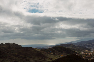 Fototapeta na wymiar City in mountains with deep rainy clouds. Tenerife. Top view