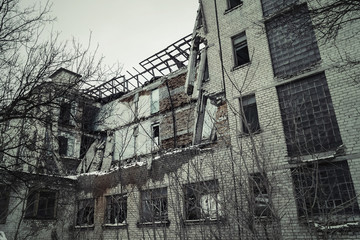 View of a dilapidated brick building. Destroyed brick facade. Toned