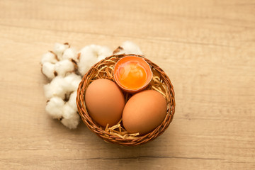 raw chicken eggs and cotton inflorescences on a wooden background

