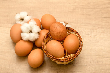 raw chicken eggs and cotton inflorescences on a wooden background
