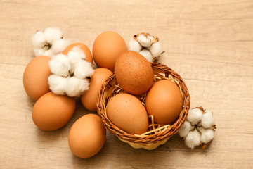 raw chicken eggs and cotton inflorescences on a wooden background
