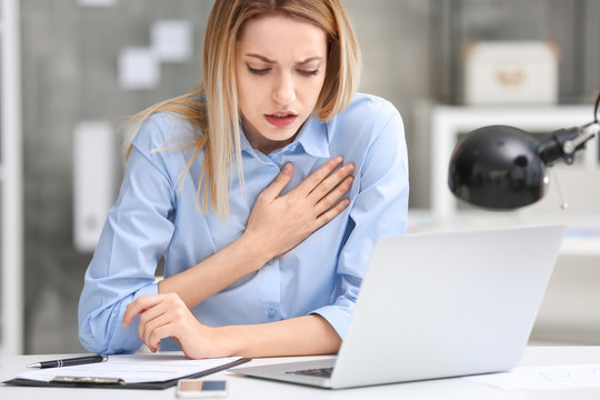 Young woman suffering from chest pain in office