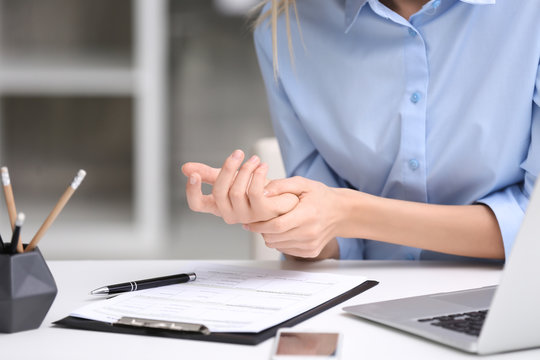 Young woman suffering from wrist pain in office