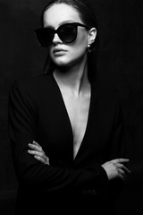 Sexy elegant black and white portrait of young beautiful woman in black deep v neck jacket and dark...