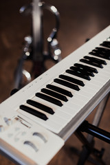 A musical instrument stands, a white keyboard synthesizer