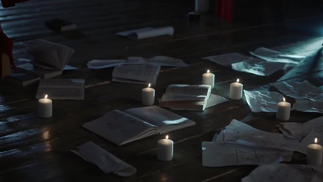Close up shot of woman's walking around spell books, candles and signs in dark. Preparing for dark ritual.