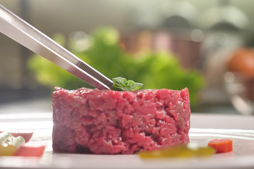 A chef prepares a gourmet dish of meat tartare and finishes the preparation with a touch of class....
