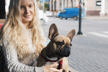 French bulldog relaxing in a cafe on blonde stylish woman's lap