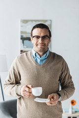 Happy man wearing glasses and holding cup of coffee