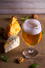 Beer and cheese. Beer glass on wooden table. Ale and appetizer snack. vertical