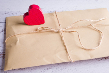 Letters in craft envelopes with a bow on on a wooden table next to a wooden heart