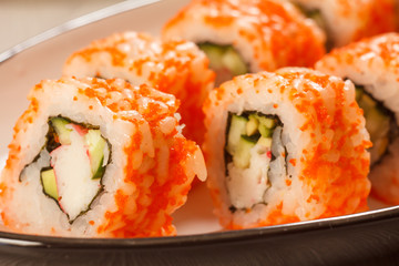 Close up Uramaki California. Sushi rolls with nori, rice, pieces of avocado, cucumber, crab sticks and flying fish roe