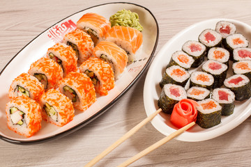 Different  sushi rolls with rice, vegetable, seafood on ceramic plates
