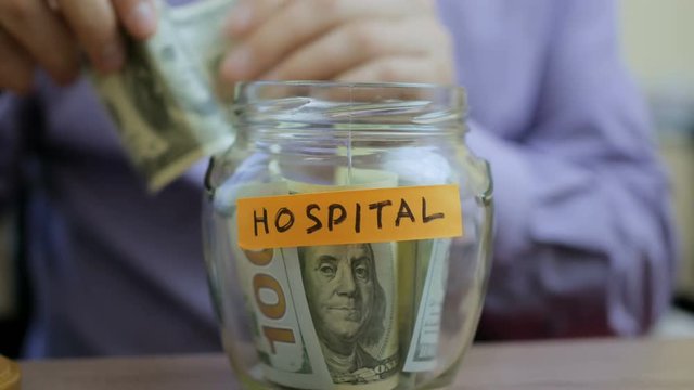 Caucasian man putting a glass jar put in a drawer table with his savings for future hospital