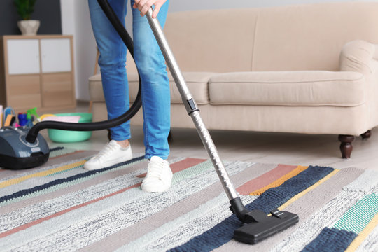 Man hoovering carpet with vacuum cleaner at home