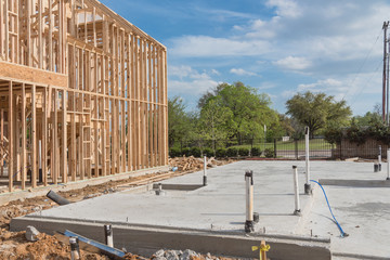 Close-up slab-on-grade foundation with timber frame house under construction in Irving, Texas, USA....