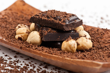 Black chocolate pieces on the wooden plate with roasted peanuts near by.