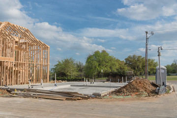 Single-family timber frame house with slab-on-grade concrete foundation footing. Construction site preparation at street corner  in suburban Irving, Texas, USA. Pile of earth, panel and portal toilets