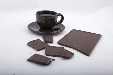 Black cup of coffee with chocolate  on gray surface